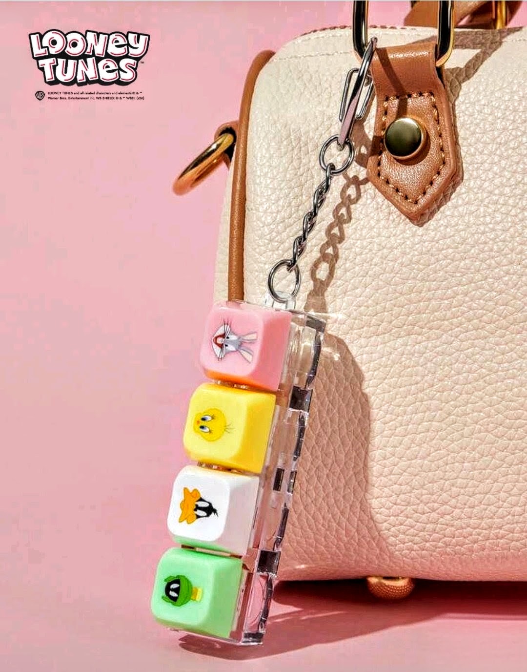 Looney Tunes clicker keychain attached to brown bag strap; four colorful character keycaps