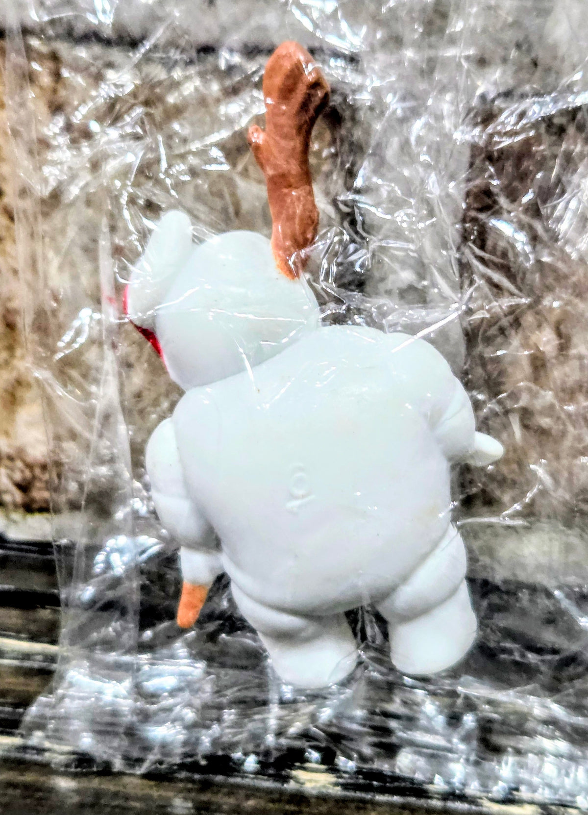Toy mini figure holding an orange roasted-marshmallow stick, wrapped in clear plastic