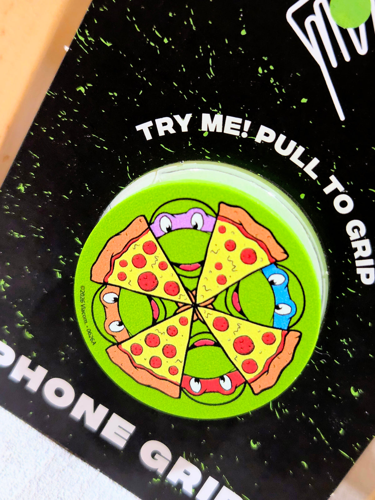 Green TMNT phone grip top with pizza-slice wheel graphic