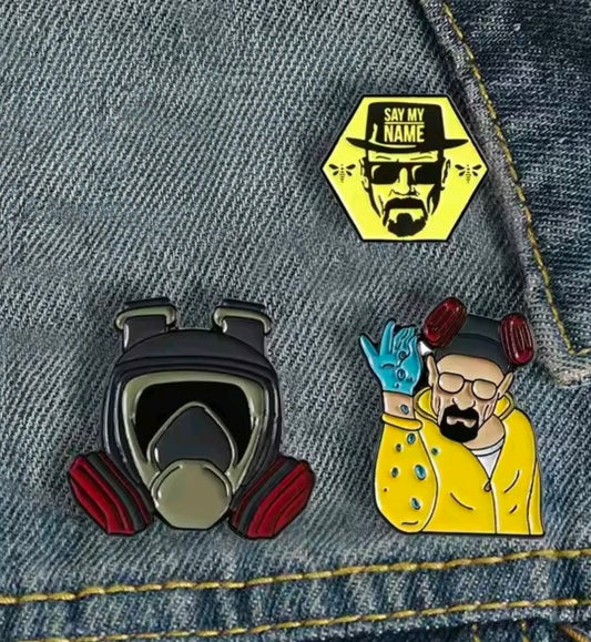 Two enamel pins on denim: gas mask and “Say My Name” hexagon portrait