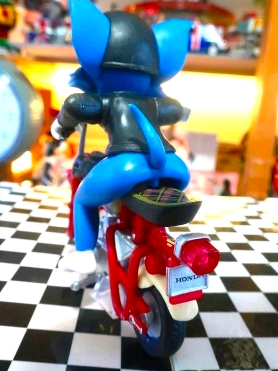 Biker Tom collectible figure in black helmet on red-and-gray motorcycle, side view