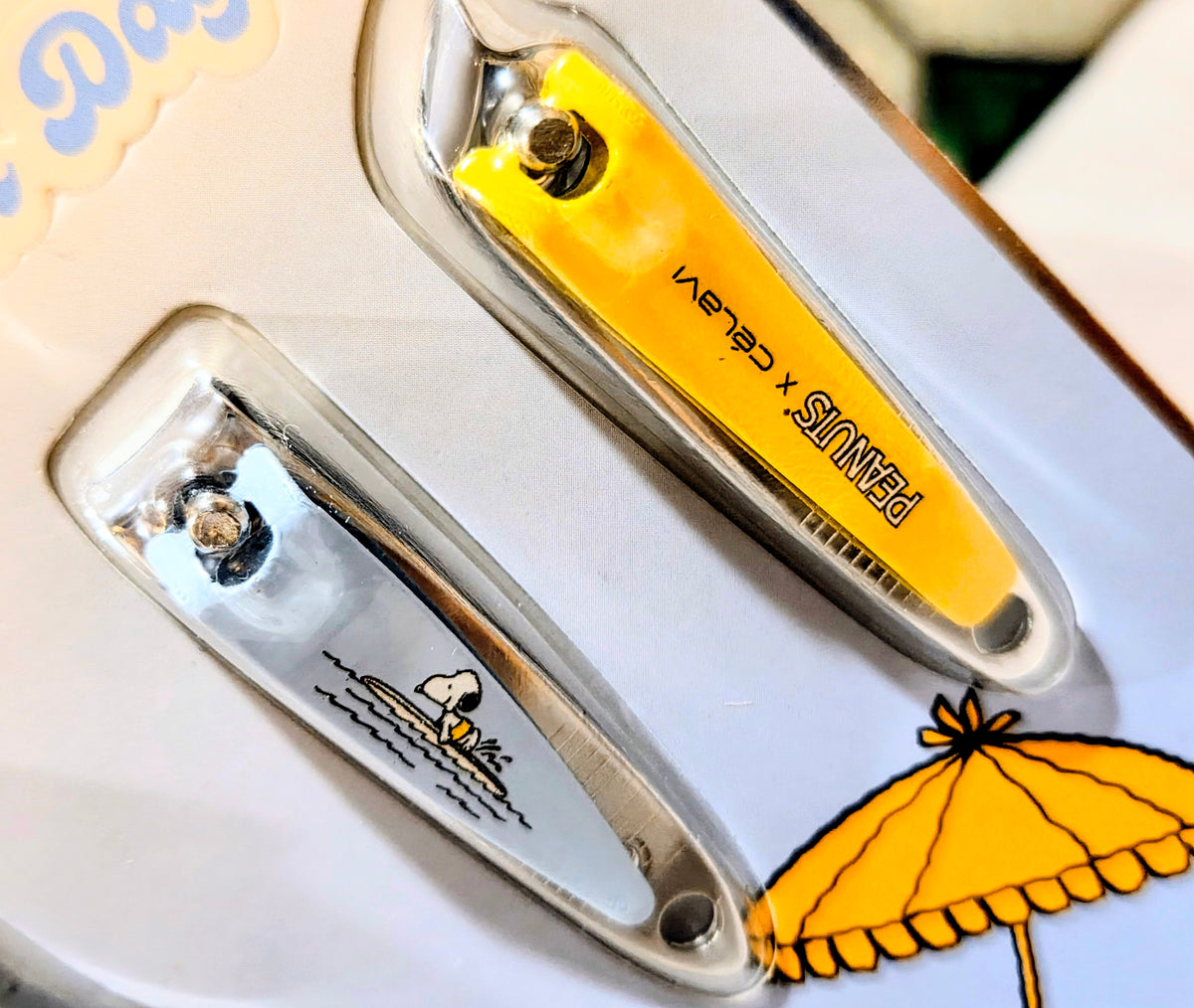 Yellow nail tool and silver clippers in a clear plastic tray