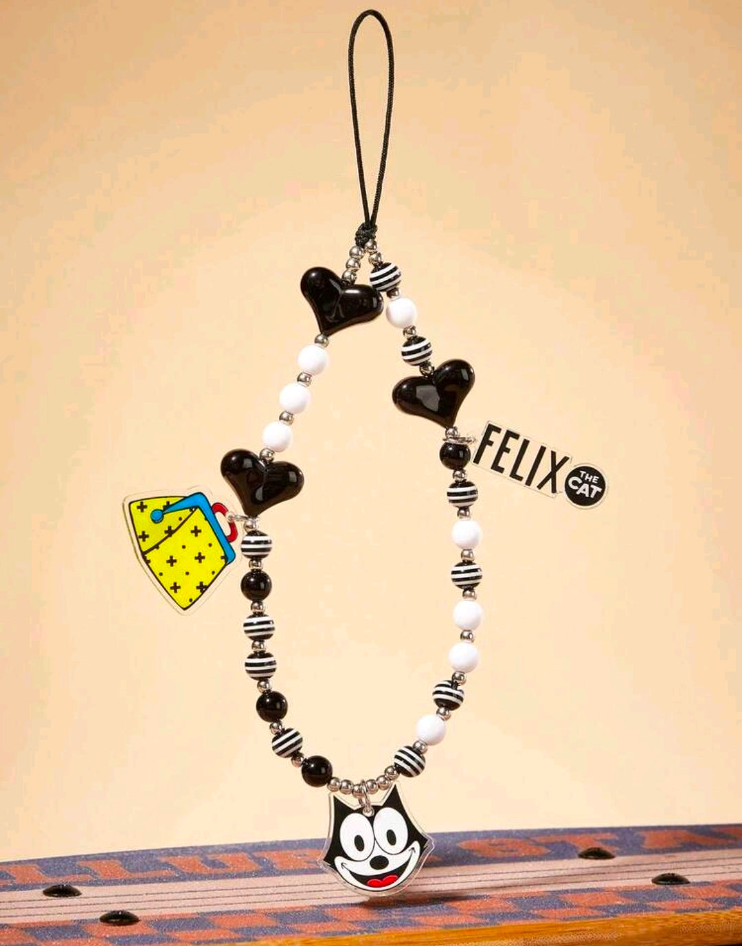 Black and white beaded phone charm lanyard with Felix face charm and striped bead accents