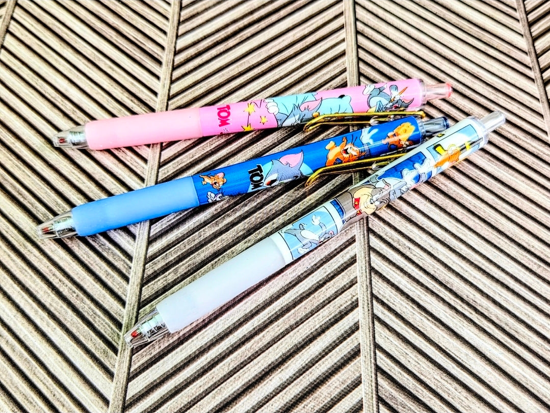 Blue and pink Tom & Jerry gel pens with decorative clip, on striped mat