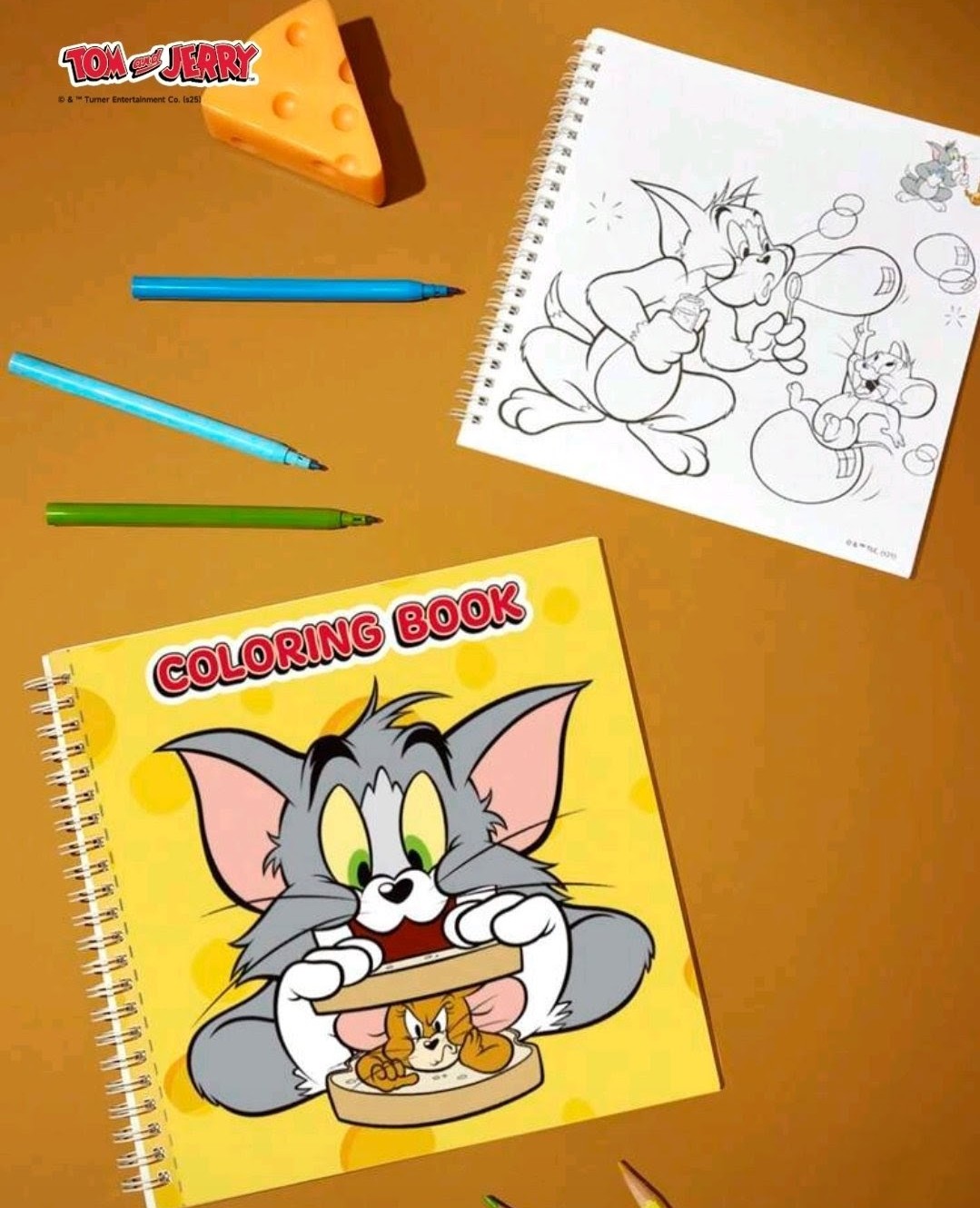 Coloring book and open sketch page with Tom and Jerry line art, crayons and cheese nearby