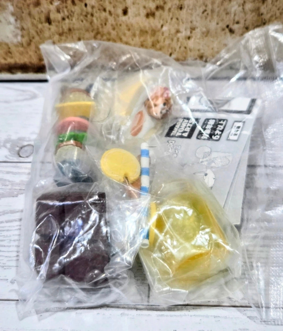 Sealed toy food figures in clear plastic with jars, chocolate, and capsule pieces