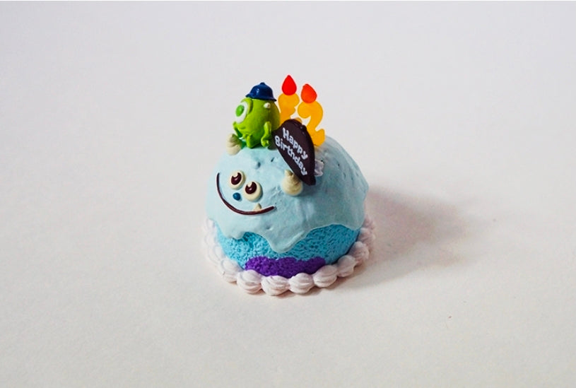Single mini birthday cake with blue monster topper, candles, and Happy Birthday card