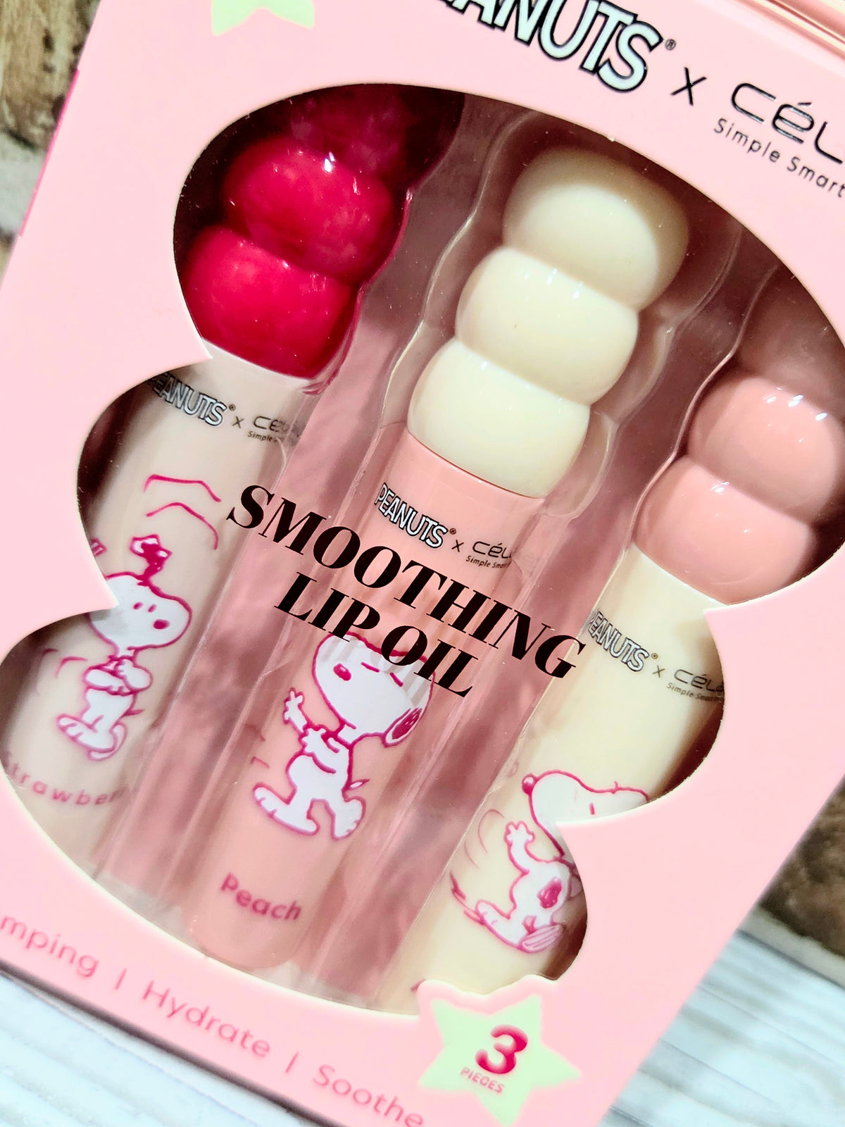 Blister tray of PEANUTS smoothing lip oils: red, cream, and pink (3)