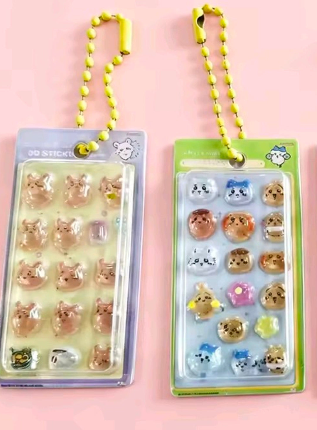 Two sticker keychains in blister packs—left blue, right green—with neon-yellow bead straps