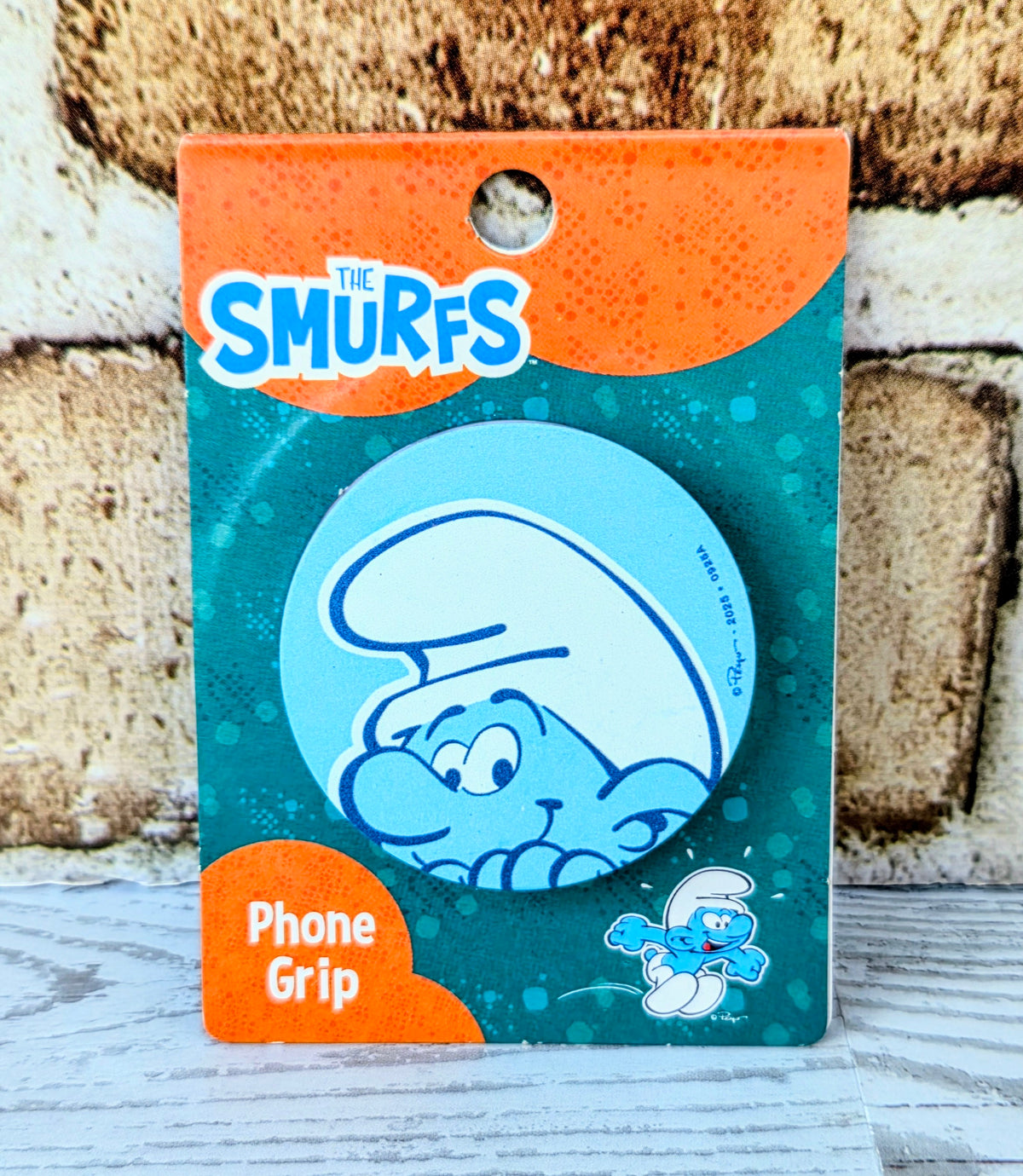 Phone grip packaging with blue circular character graphic and orange label