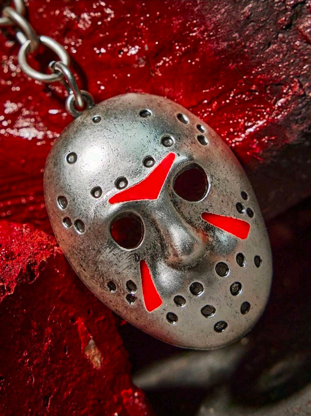 Antique silver hockey mask keychain charm with red-and-black detailing and rivet holes