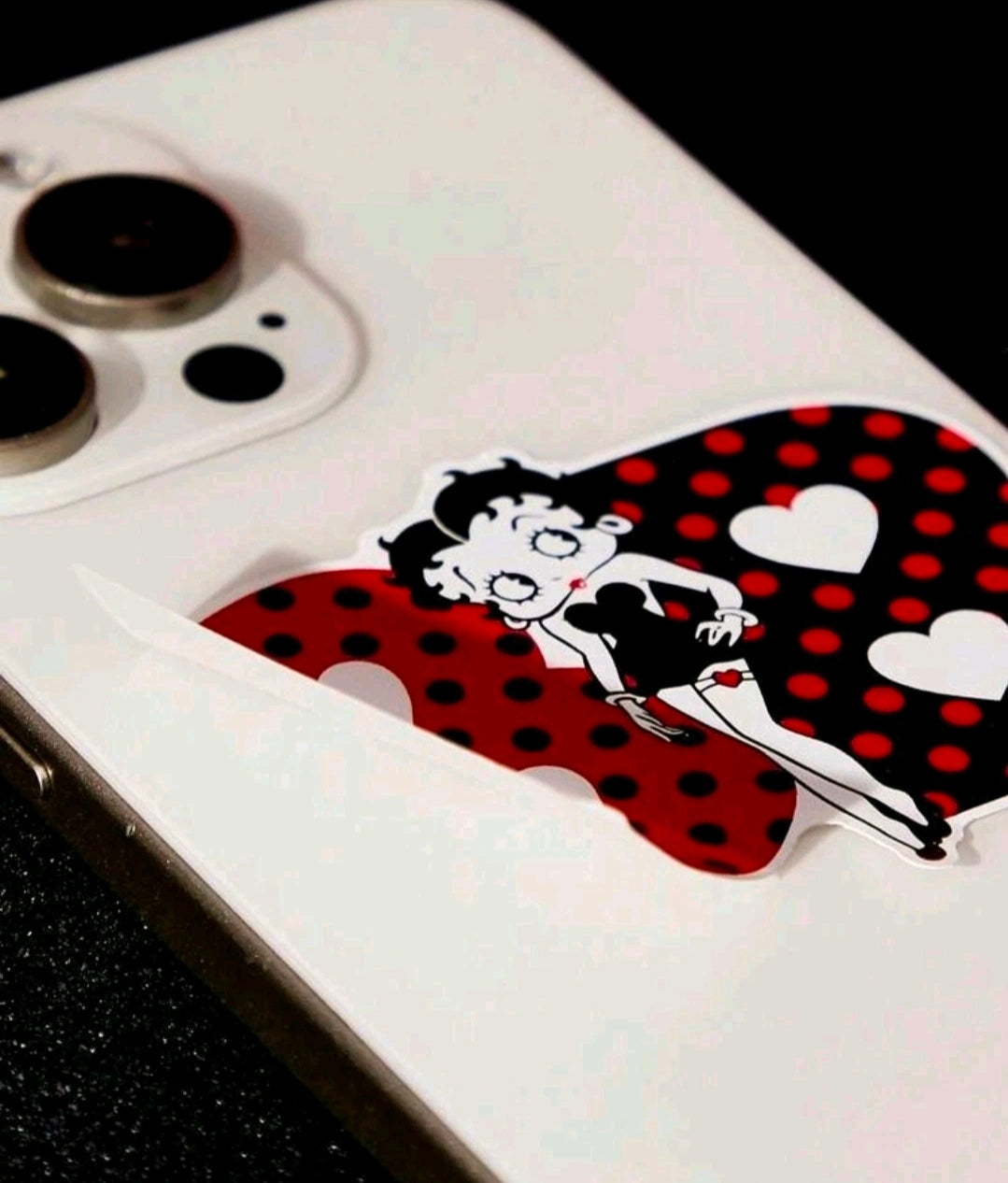 White phone with Betty Boop red polka-dot heart character sticker on the back