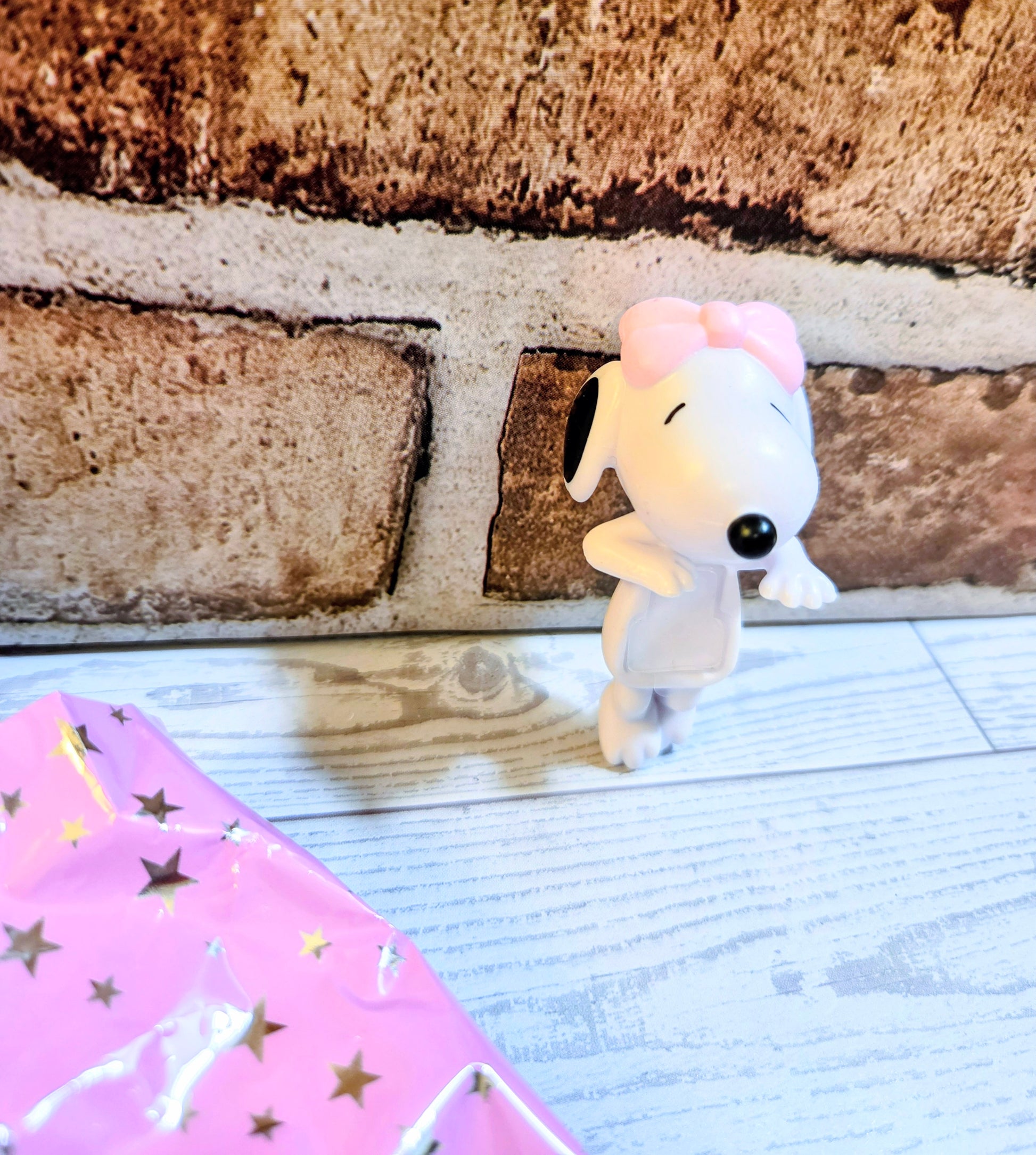 Side view white mini figure with pink bow, black eyes, crouched