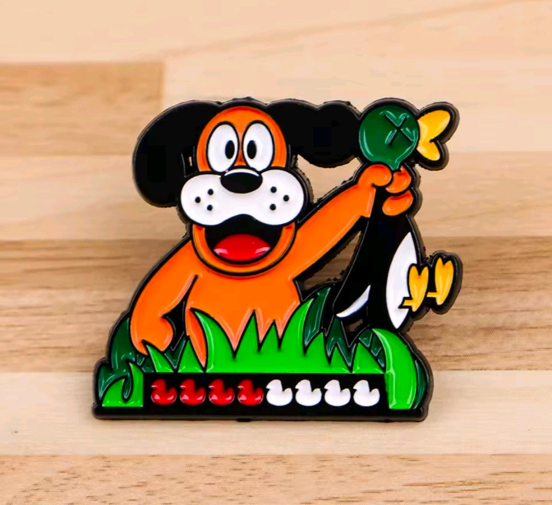 Orange cartoon dog enamel lapel pin in green grass with red details.