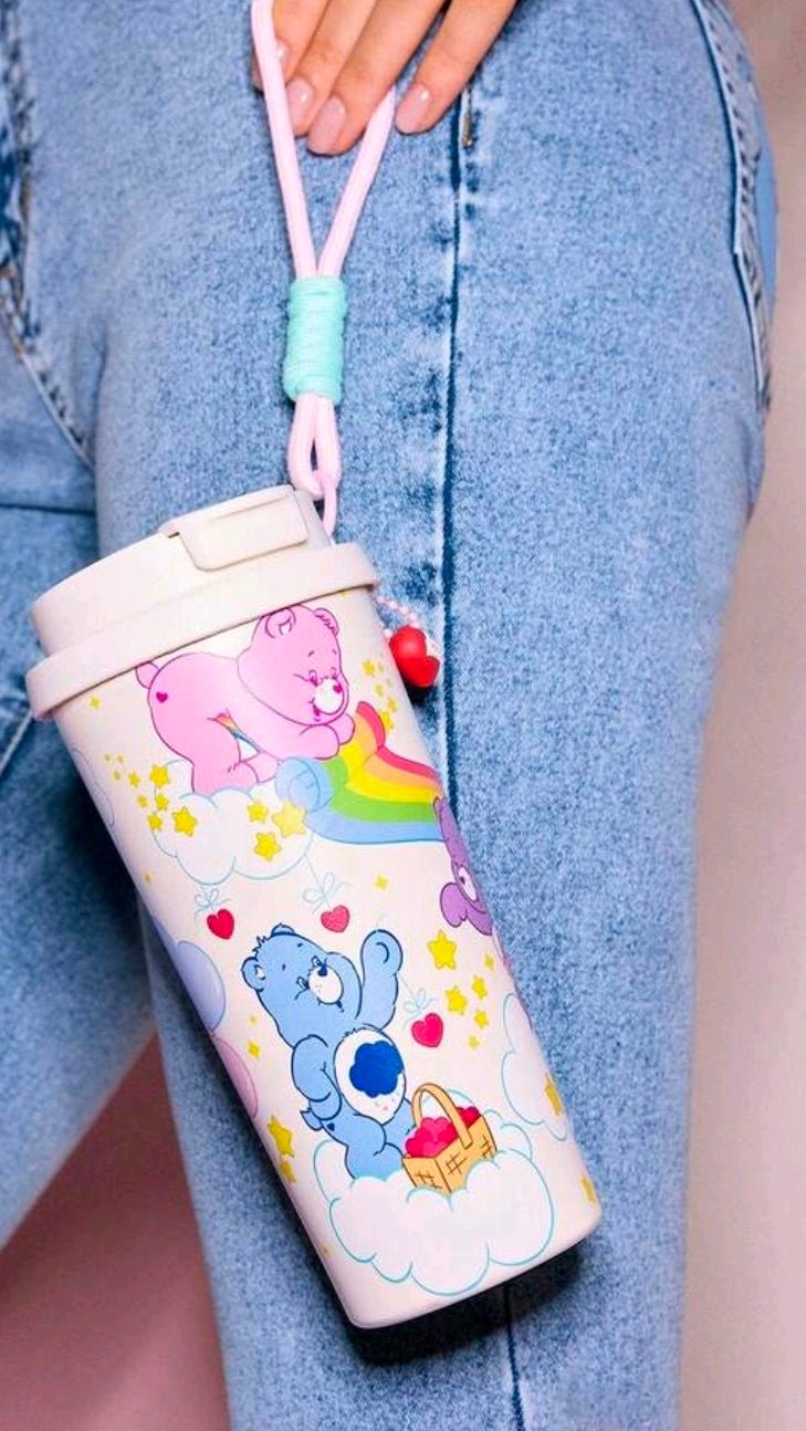 White Care Bears insulated tumbler hanging from pink strap on blue denim