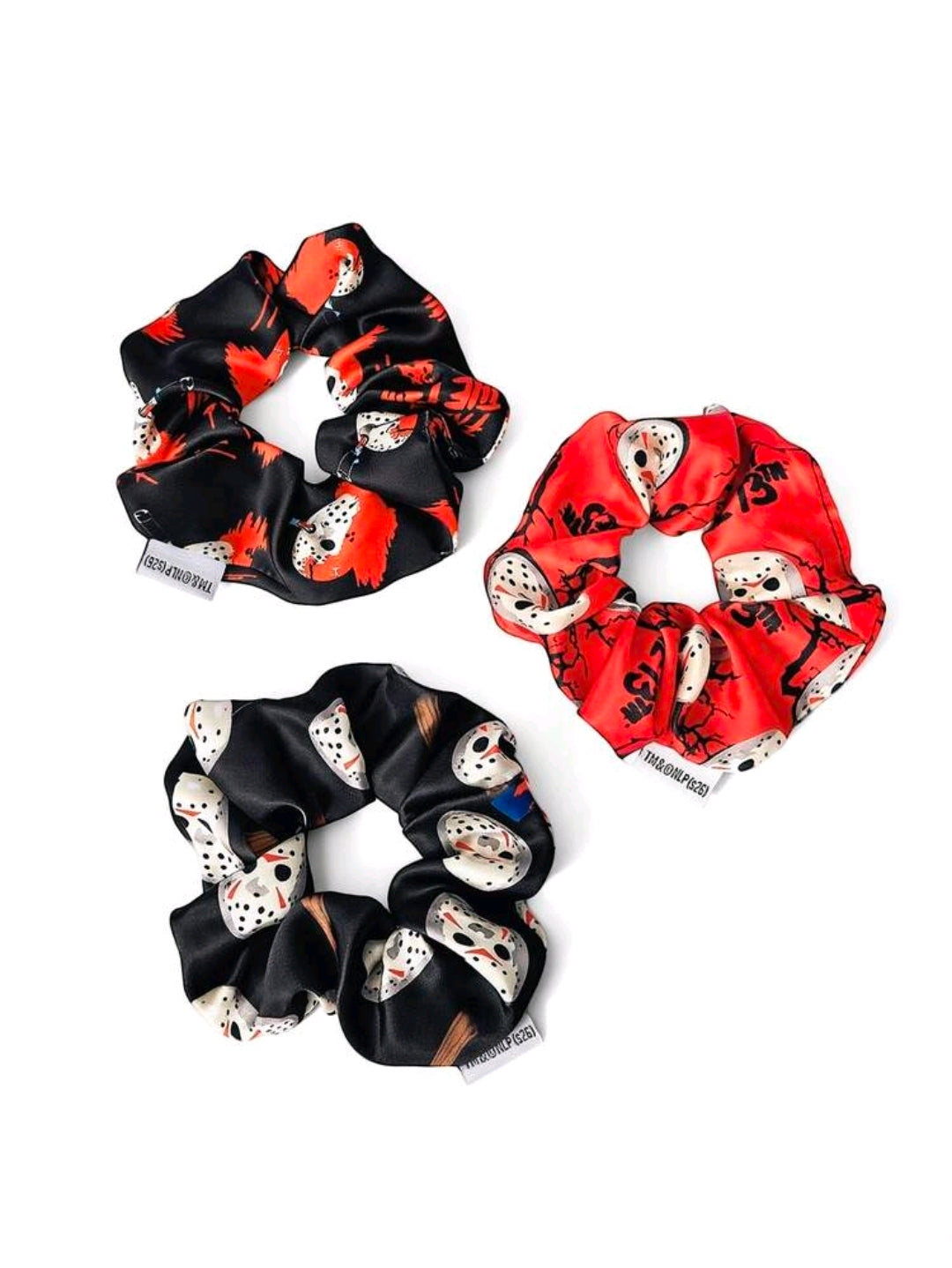 Three scrunchies with red, black, and mixed prints featuring Jason-style mask graphics