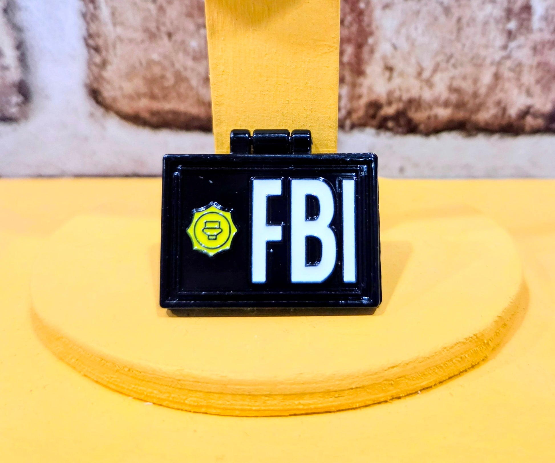 Rectangular enamel pin with “FBI” letters and badge icon on dark blue background.