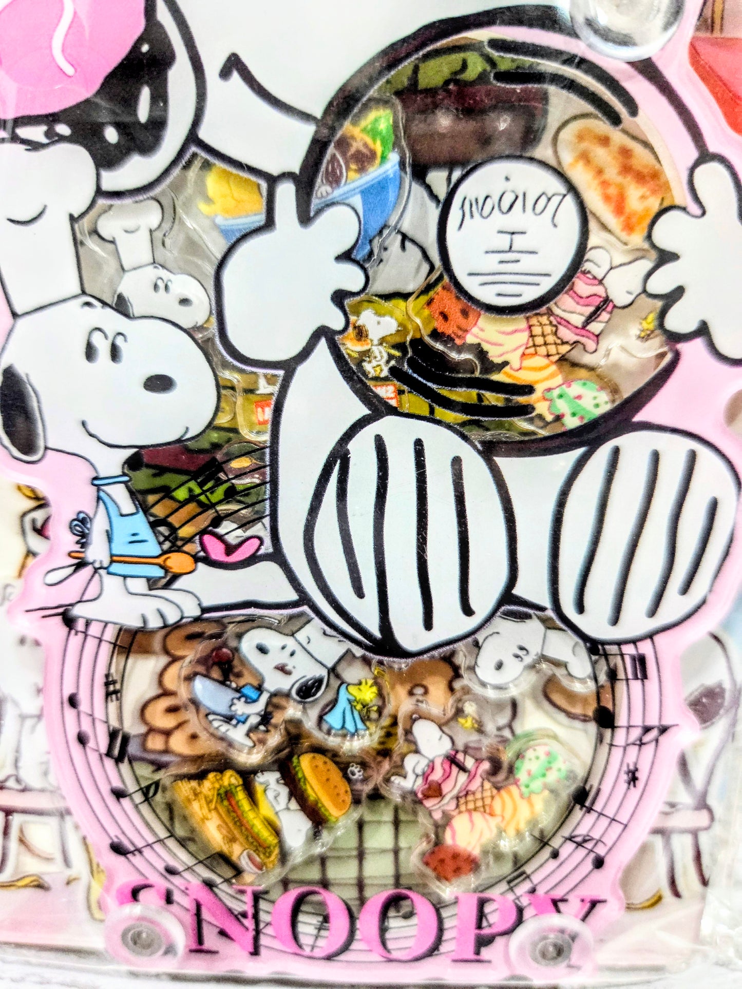 Pink acrylic shaker notebook cover close-up with Snoopy chef hat and food collage