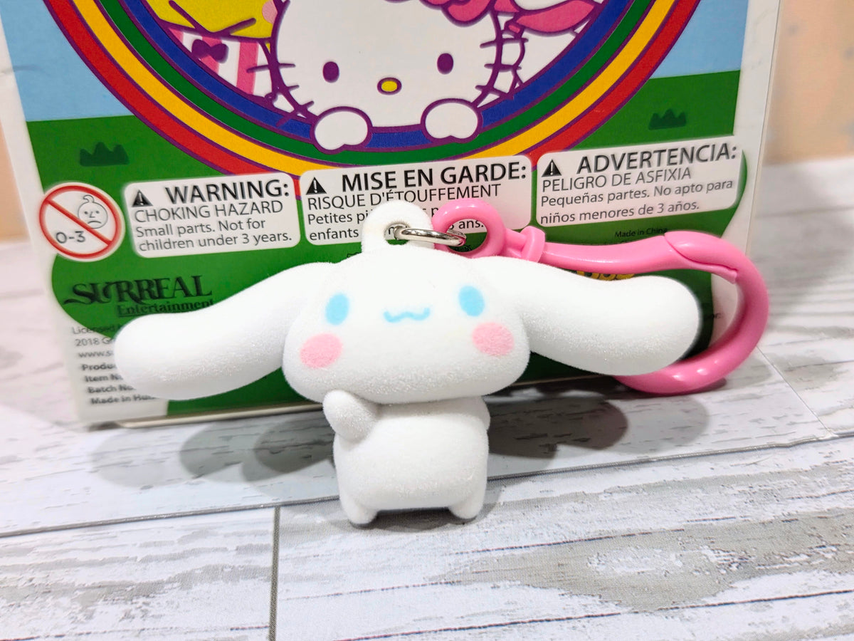 White flocked character keychain with light blue and pink details, pink ring visible.