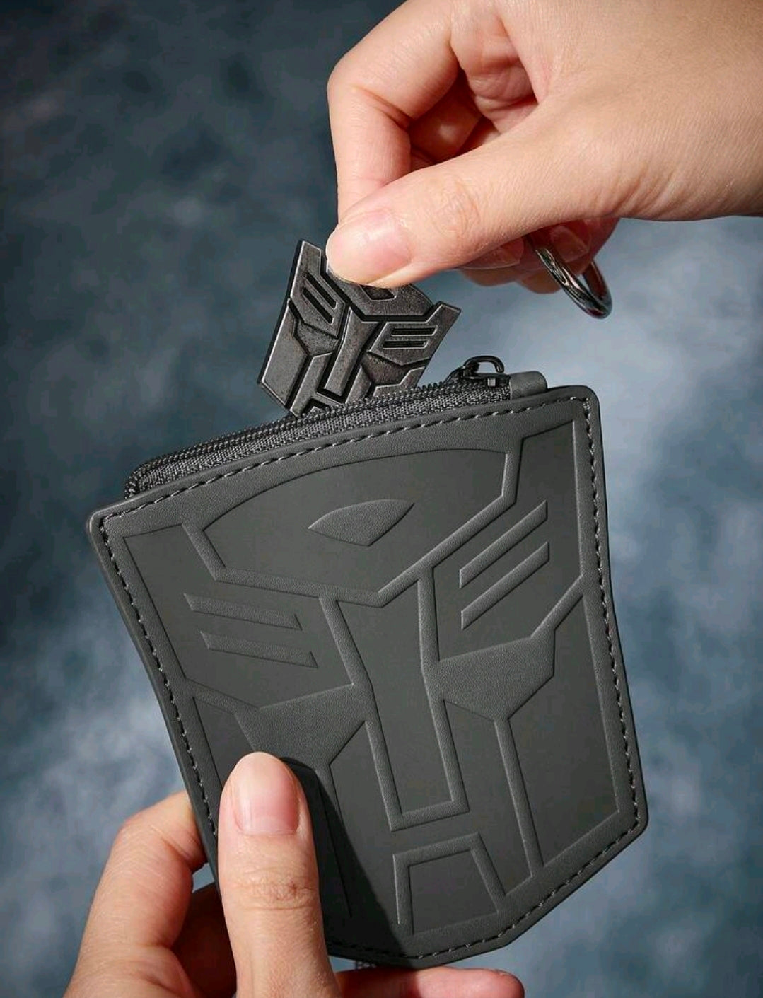 Dark gray zippered coin purse with embossed Autobot logo, small keychain ring