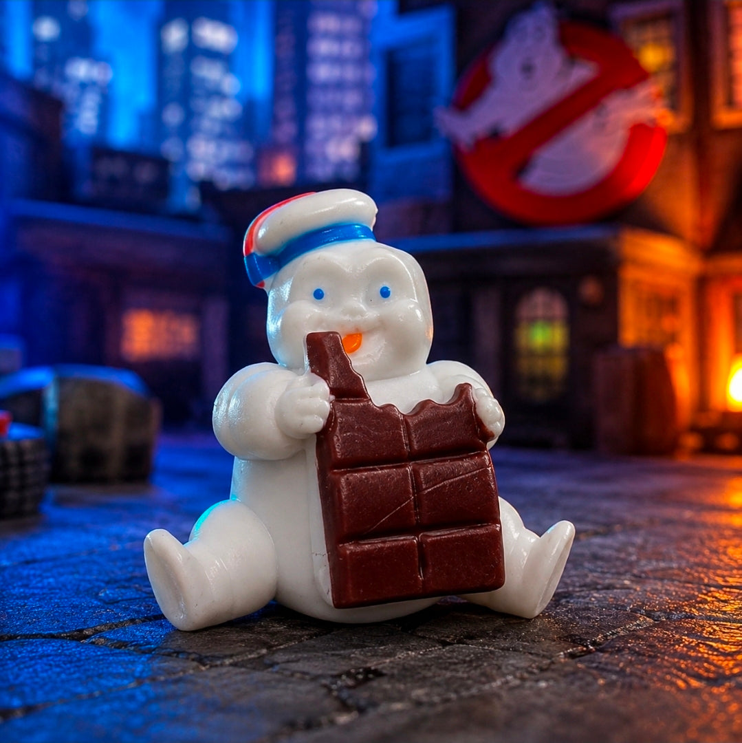White mini Puft figure seated holding a brown chocolate block, striped hat.