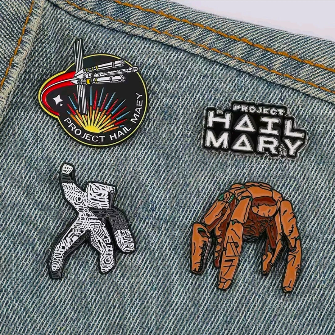 4-piece enamel pin set on denim featuring character pins, text logo pin, and spaceship emblem
