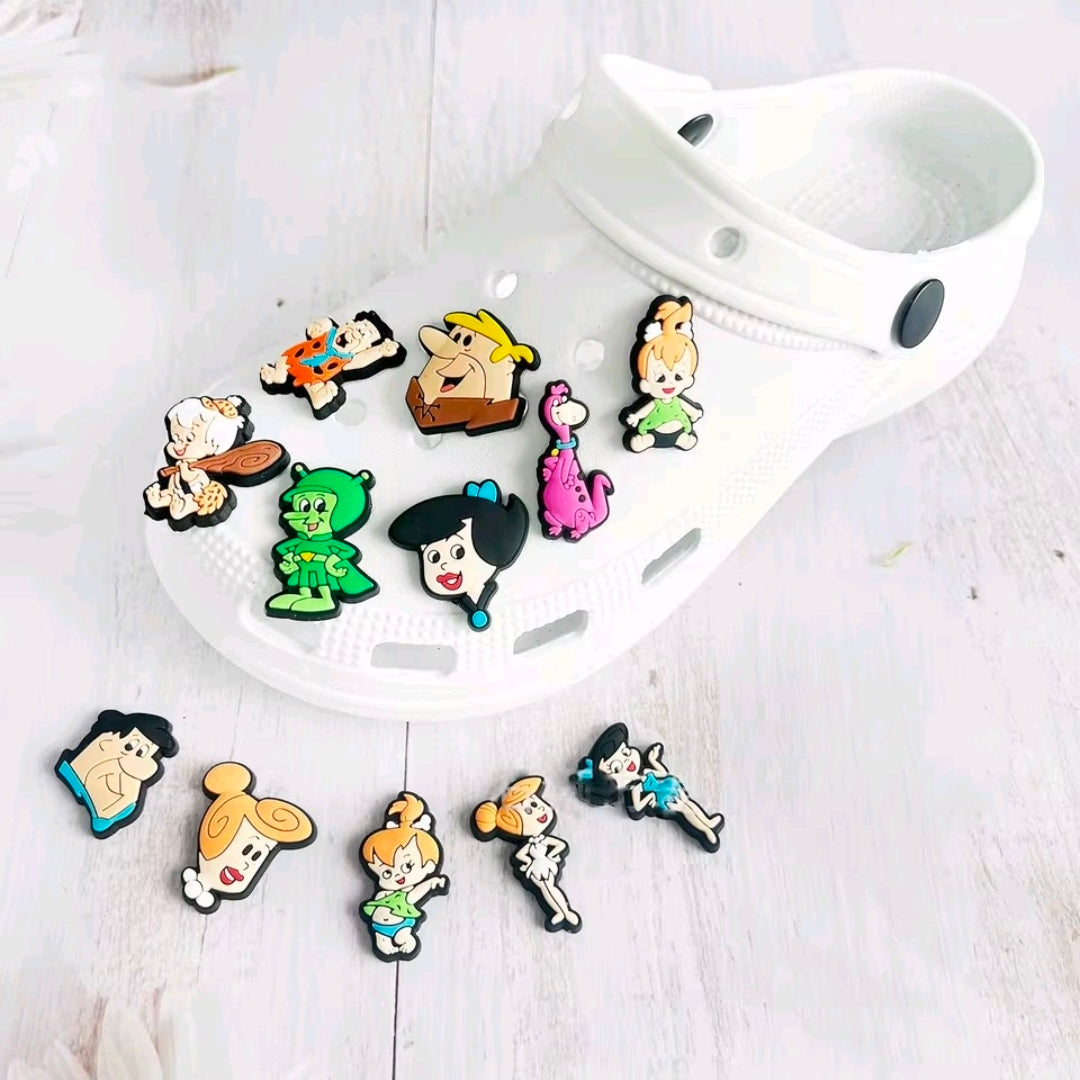 Assorted small cartoon shoe and bag charms scattered on a white clog