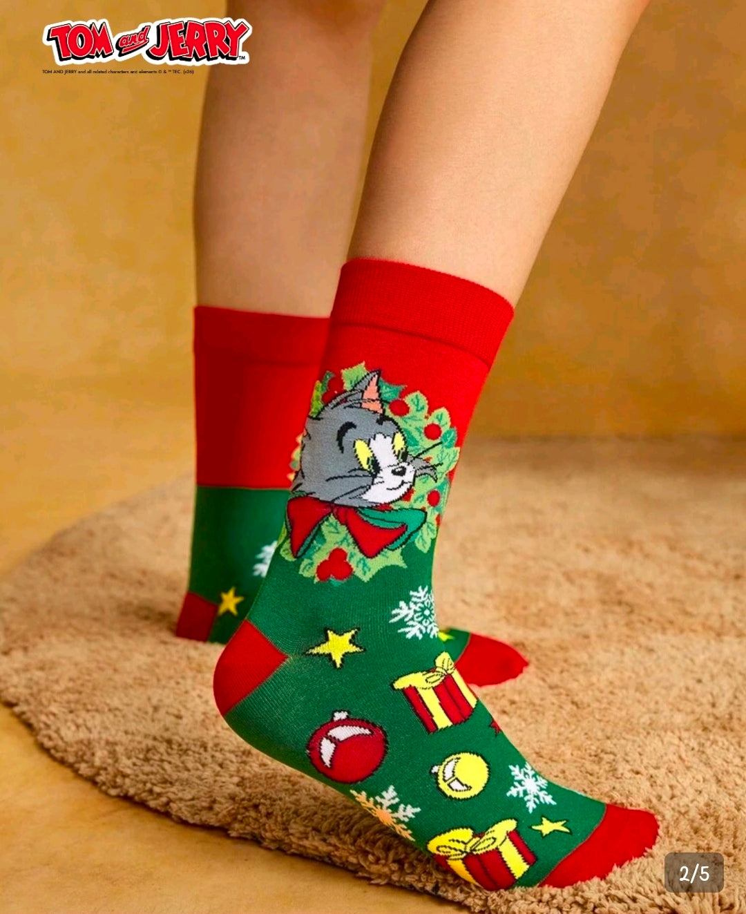 Tom & Jerry holiday crew sock on foot, green with red cuff and festive icons