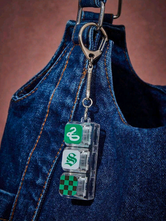 Slytherin fidget keychain charm hanging from blue denim with green snake blocks