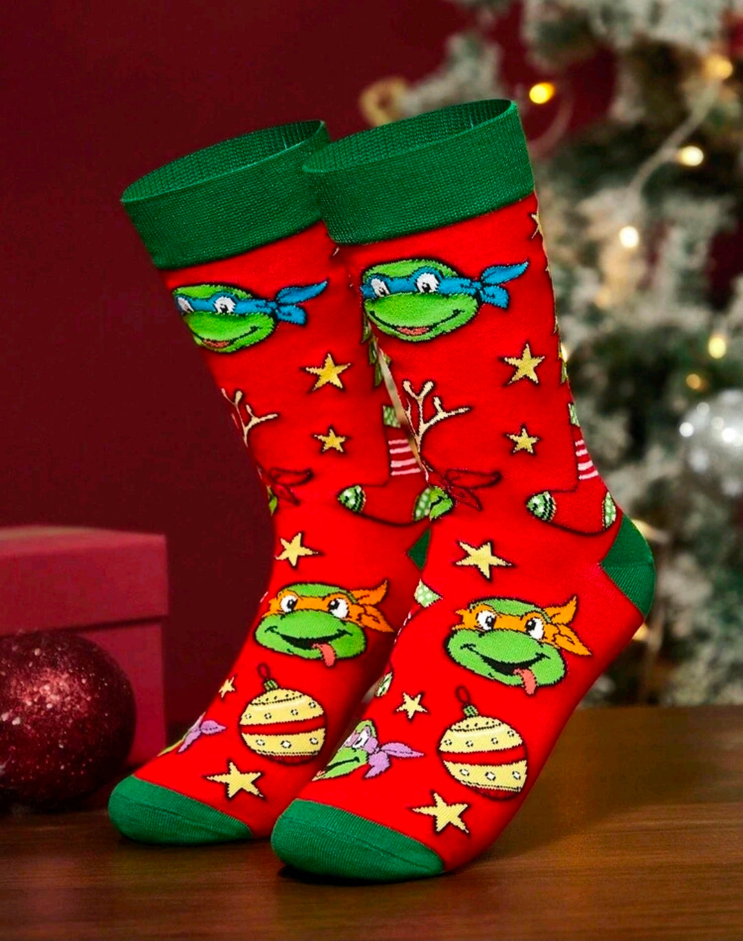 Red crew socks with green cuffs and cartoon turtle Christmas icons on a wooden floor