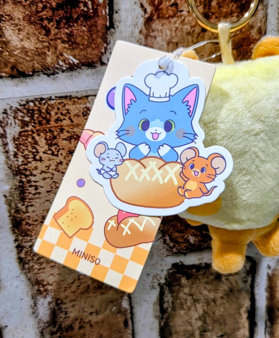 Yellow toast plush keychain with cartoon patch tag featuring a blue cat and mouse