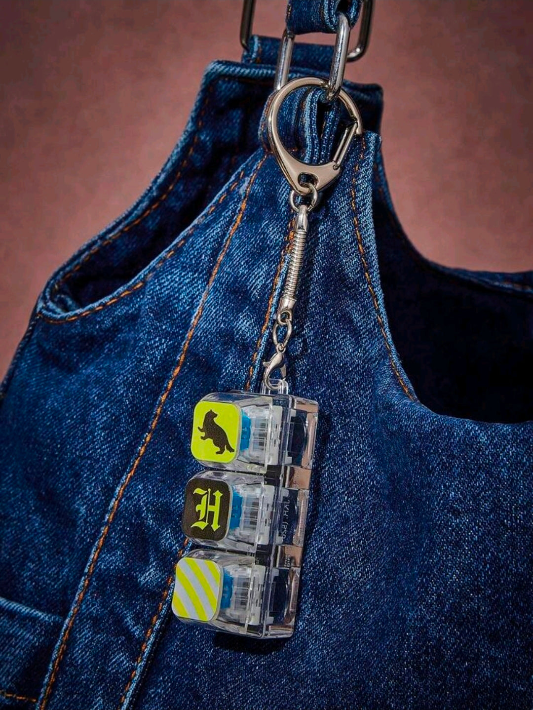 Hufflepuff acrylic clicker keychain charm on blue denim bag with metal keyring