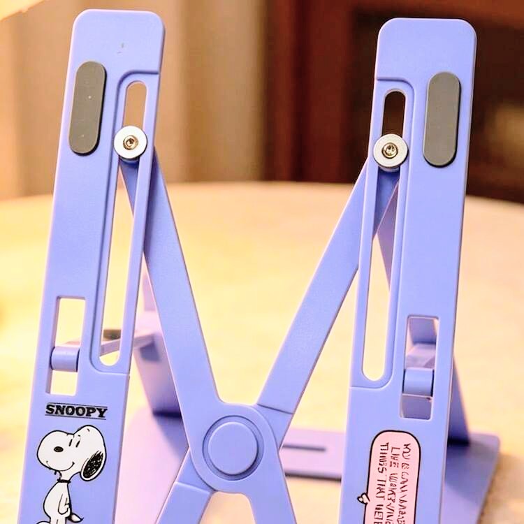 Purple foldable laptop stand with central hinge and Snoopy decal on arms
