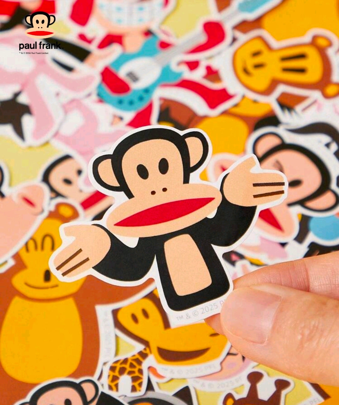 Hand placing a paul frank vinyl sticker of a monkey holding a sign and heart