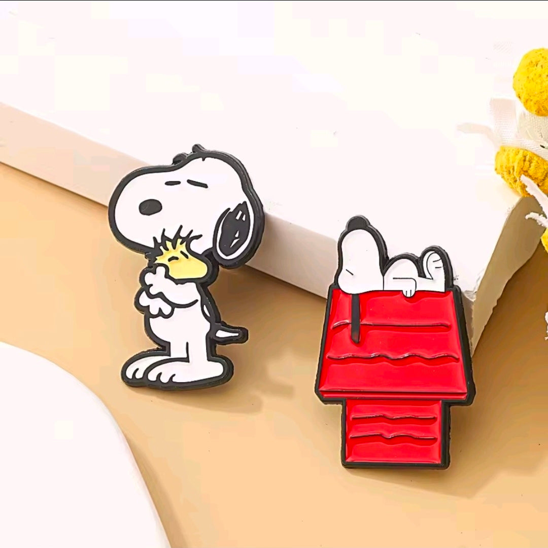 Snoopy and red bag enamel pins on display, black outlines and bright red details