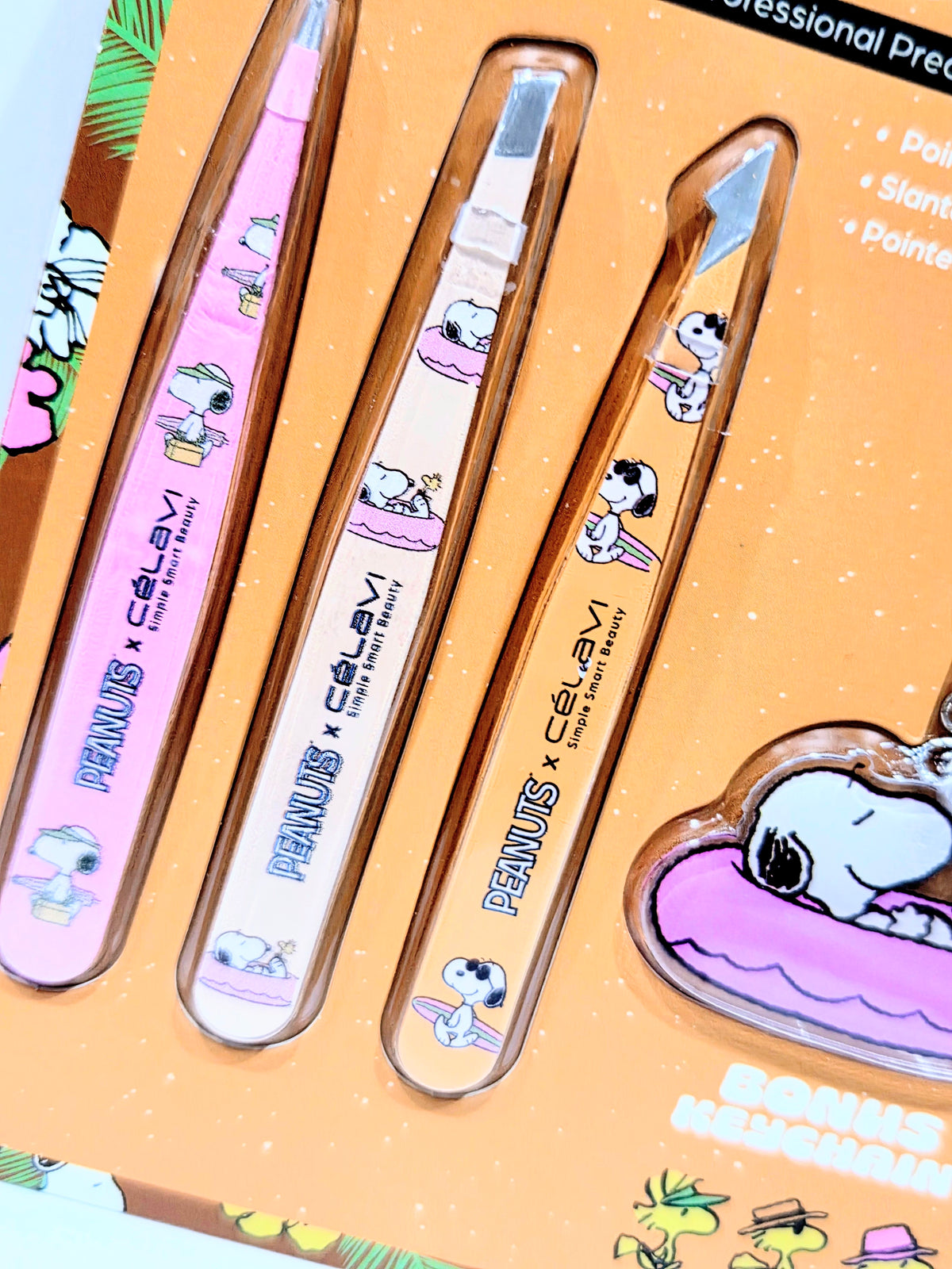 Three illustrated slant-point tweezers shown in blister pack next to keychain charm.