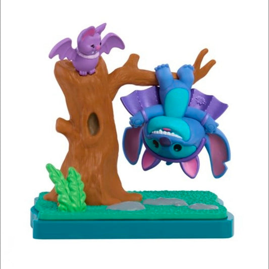 Stitch blind box figure in blue costume, perched on tree stump with purple figure