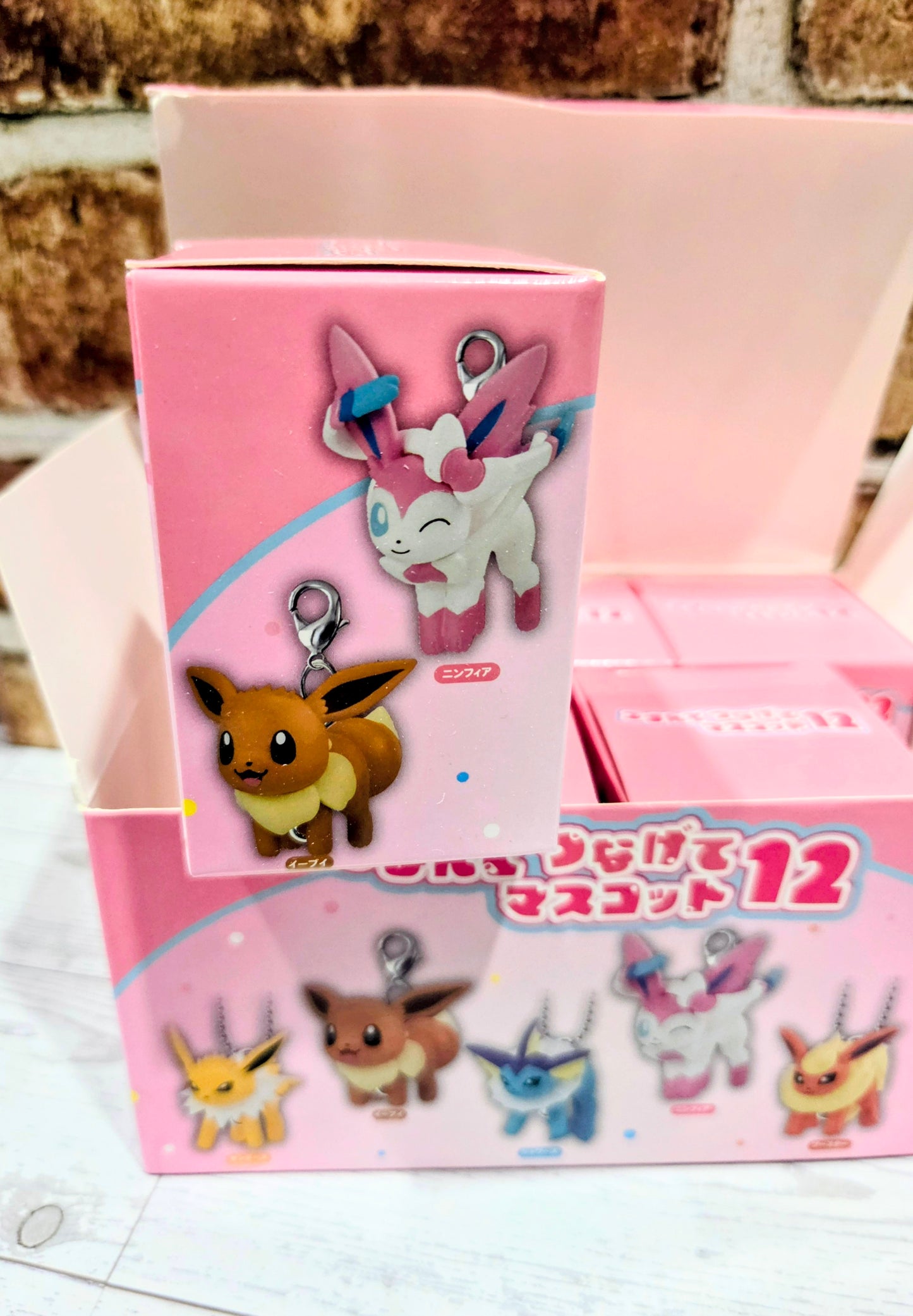 Open pink keychain blind box with Pokémon character charm graphics and display tray