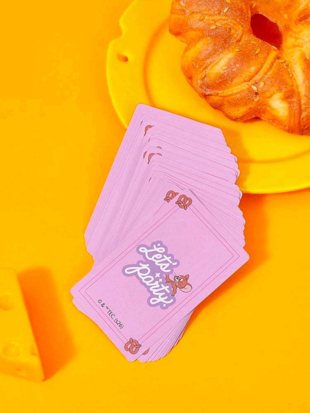 Purple “Let’s Party” playing cards fanned on bright yellow surface
