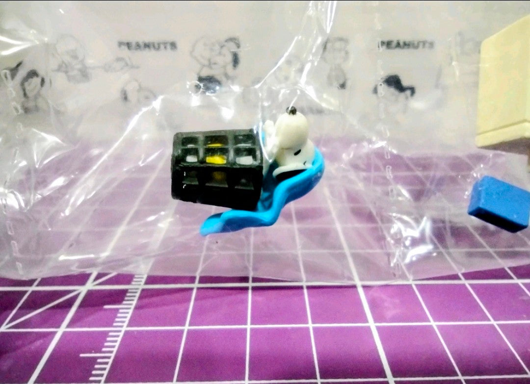 Small Snoopy figure carrying a black crate with yellow and green details