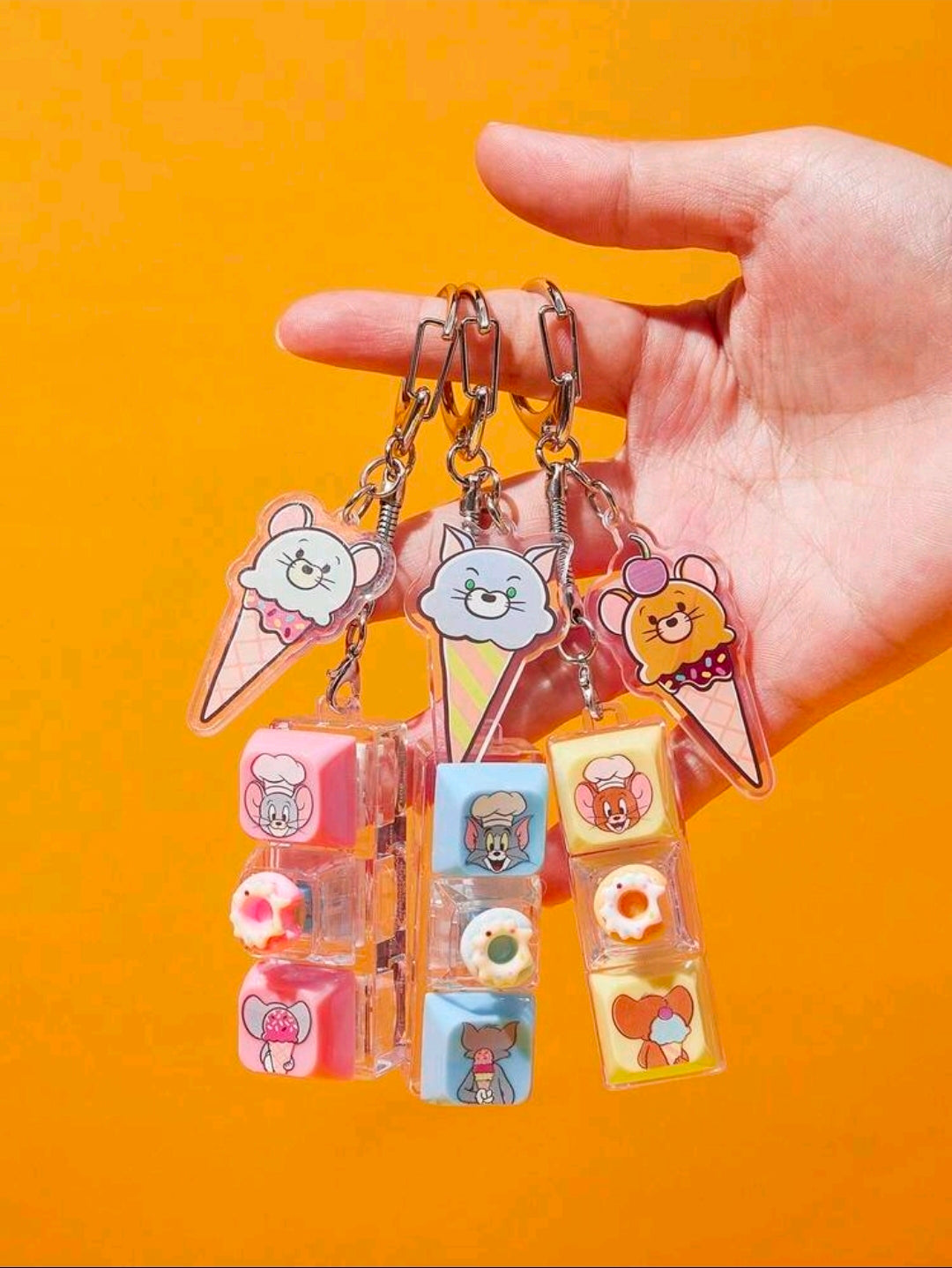 Hand holding Tom & Jerry dessert keyboard fidget clicker keychains with clear cube blocks