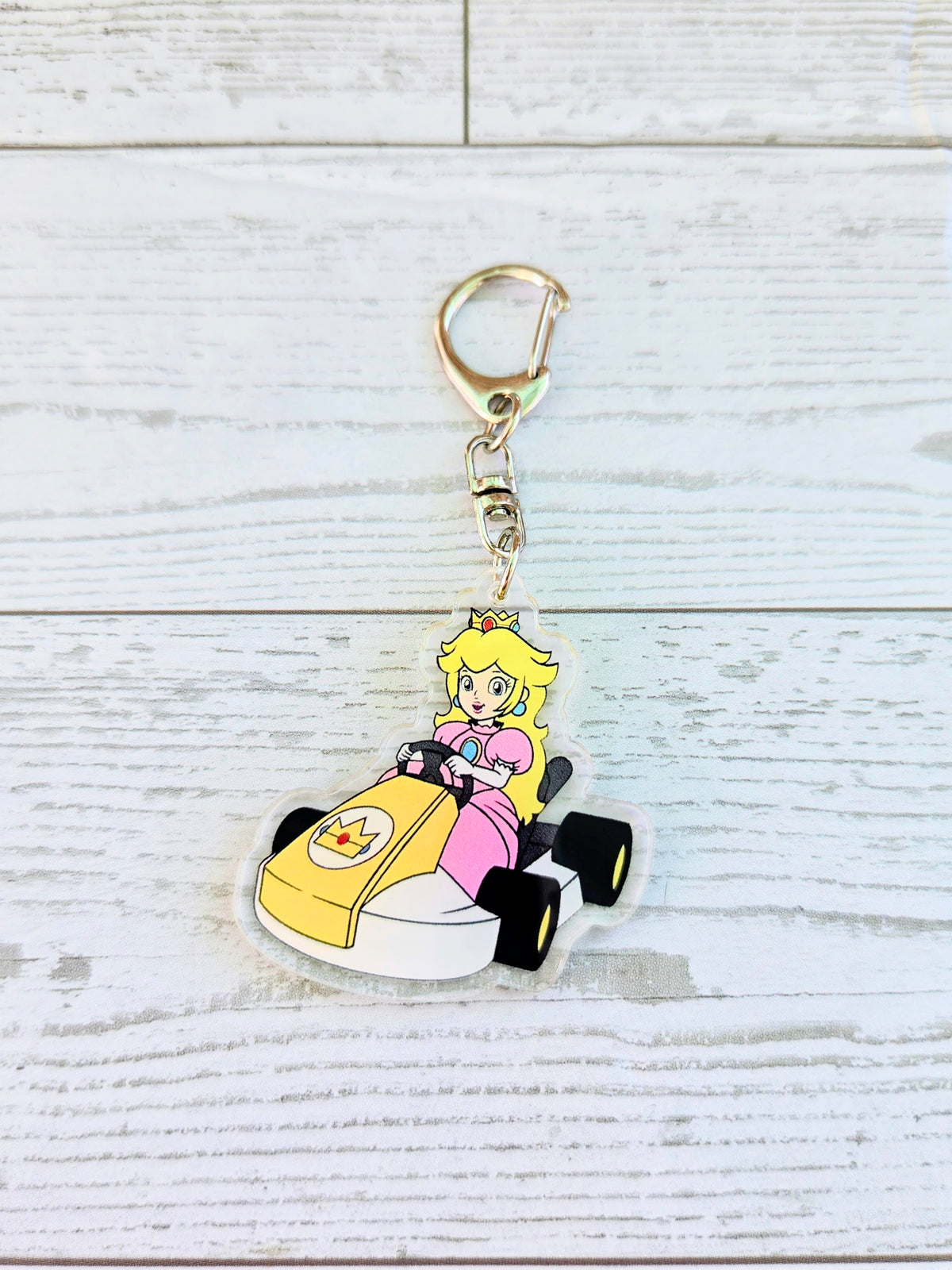 Acrylic die-cut keychain of Princess Peach in a racing cart with gold keyring