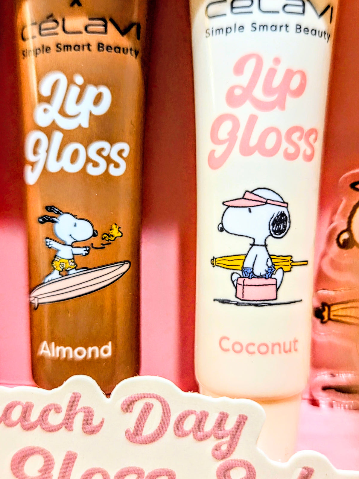 Close-up of almond and coconut lip gloss tubes with Peanuts beach character prints
