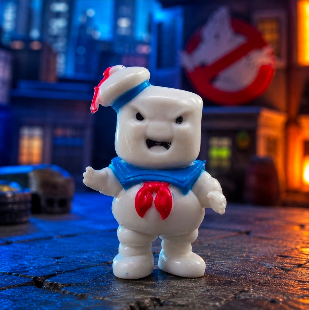 White mini figure standing, blue bib and red chest emblem, red-tipped hat, posed