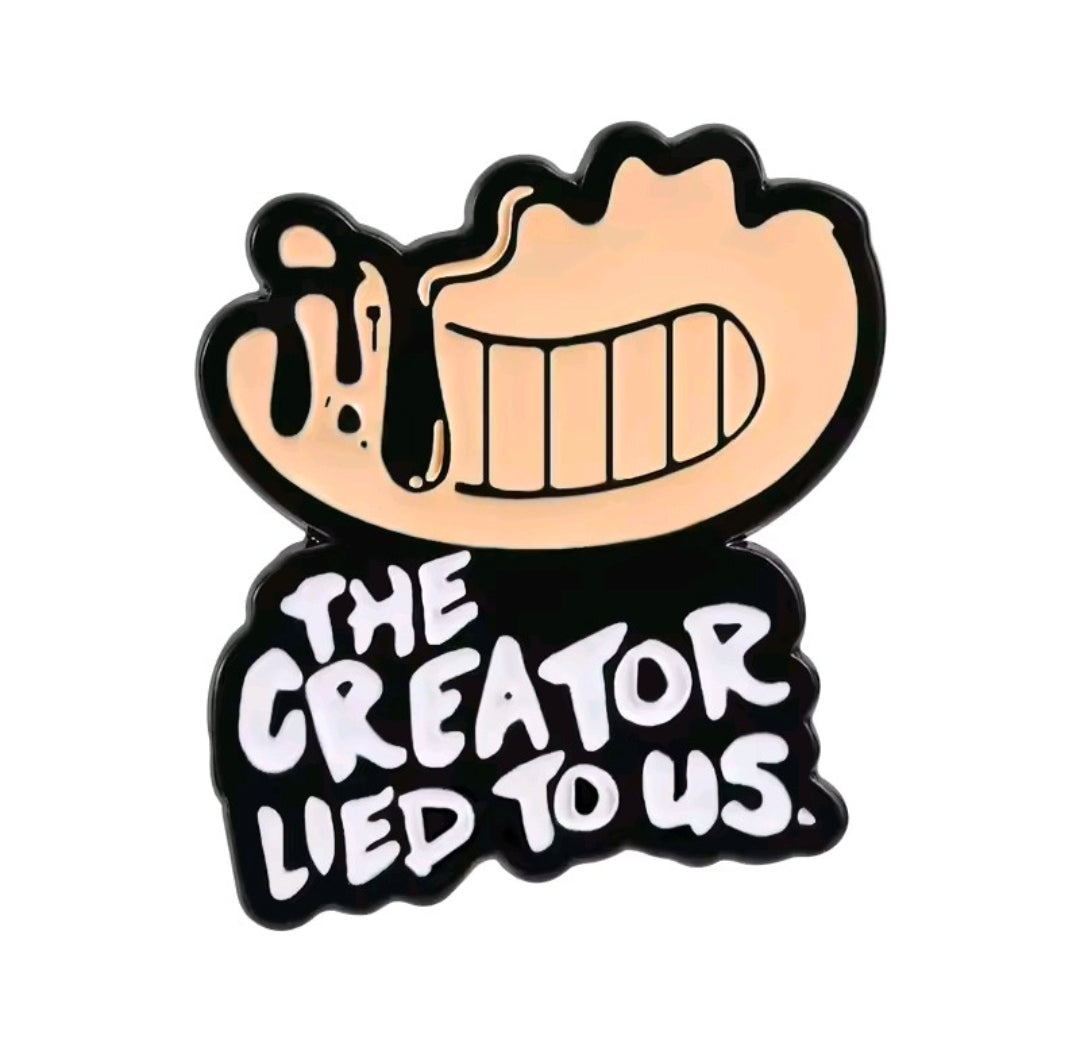 Enamel pin featuring a black character with a wide toothy grin and the words The Creator Lied to Us