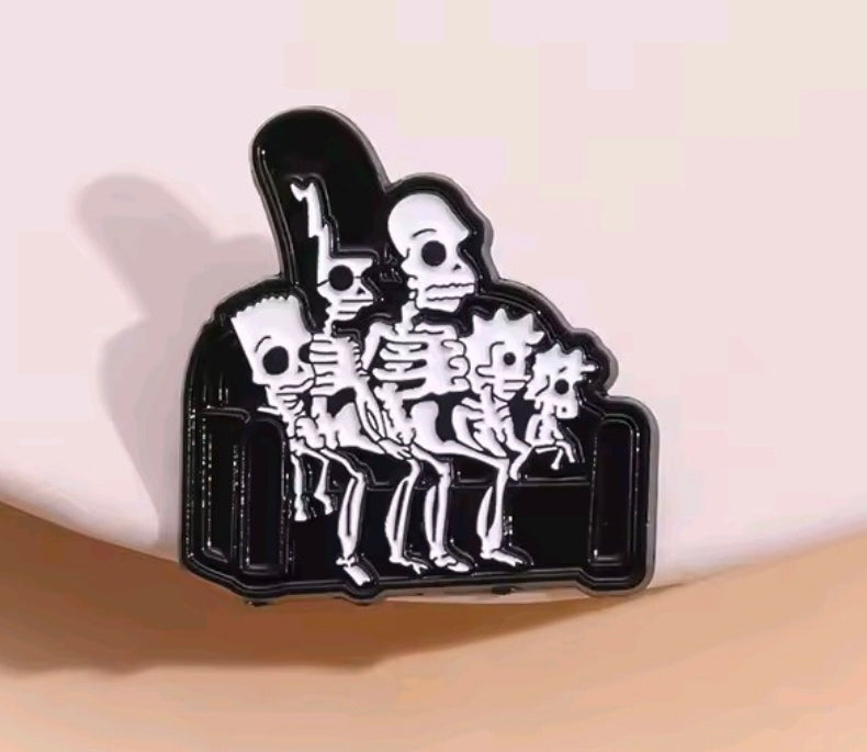 Enamel pin showing a skeleton group under a dark arch frame with black outline
