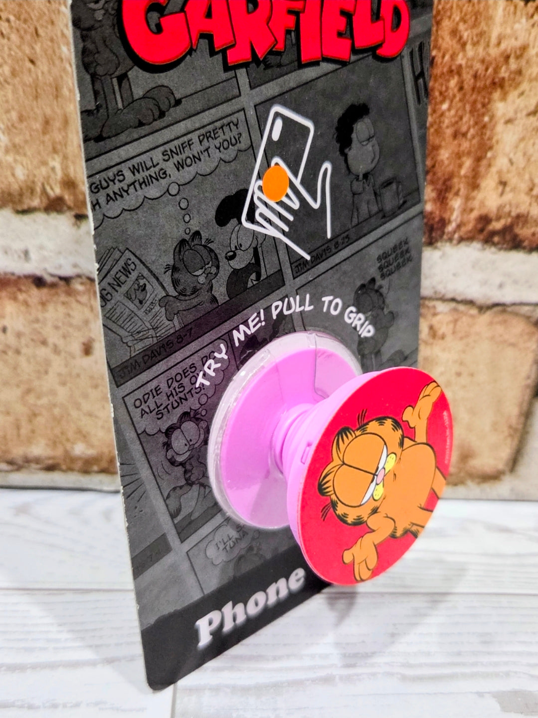 Garfield phone grip holder with purple adhesive pad and red pop socket disc showing Garfield.