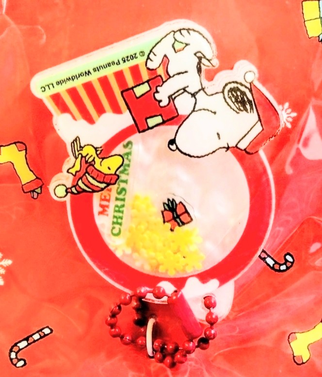 Orange Snoopy Christmas charm featuring Snoopy holding a gift inside a circle