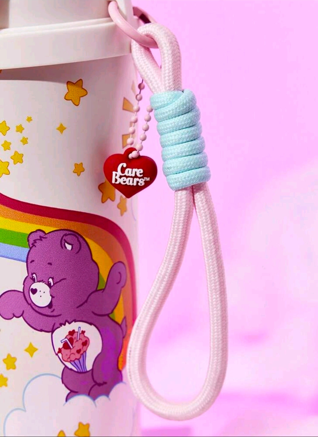 White tumbler with Care Bears print and light blue wrist strap with red charm