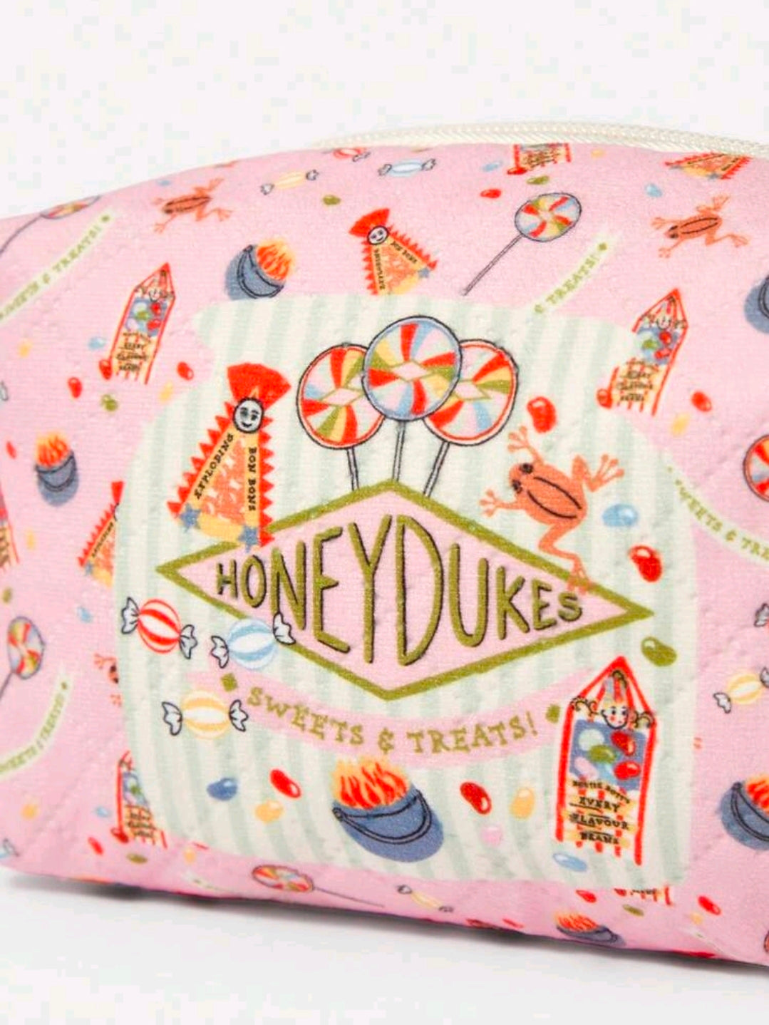 Pink makeup pouch close-up with Honeydukes sign graphic and candy icons